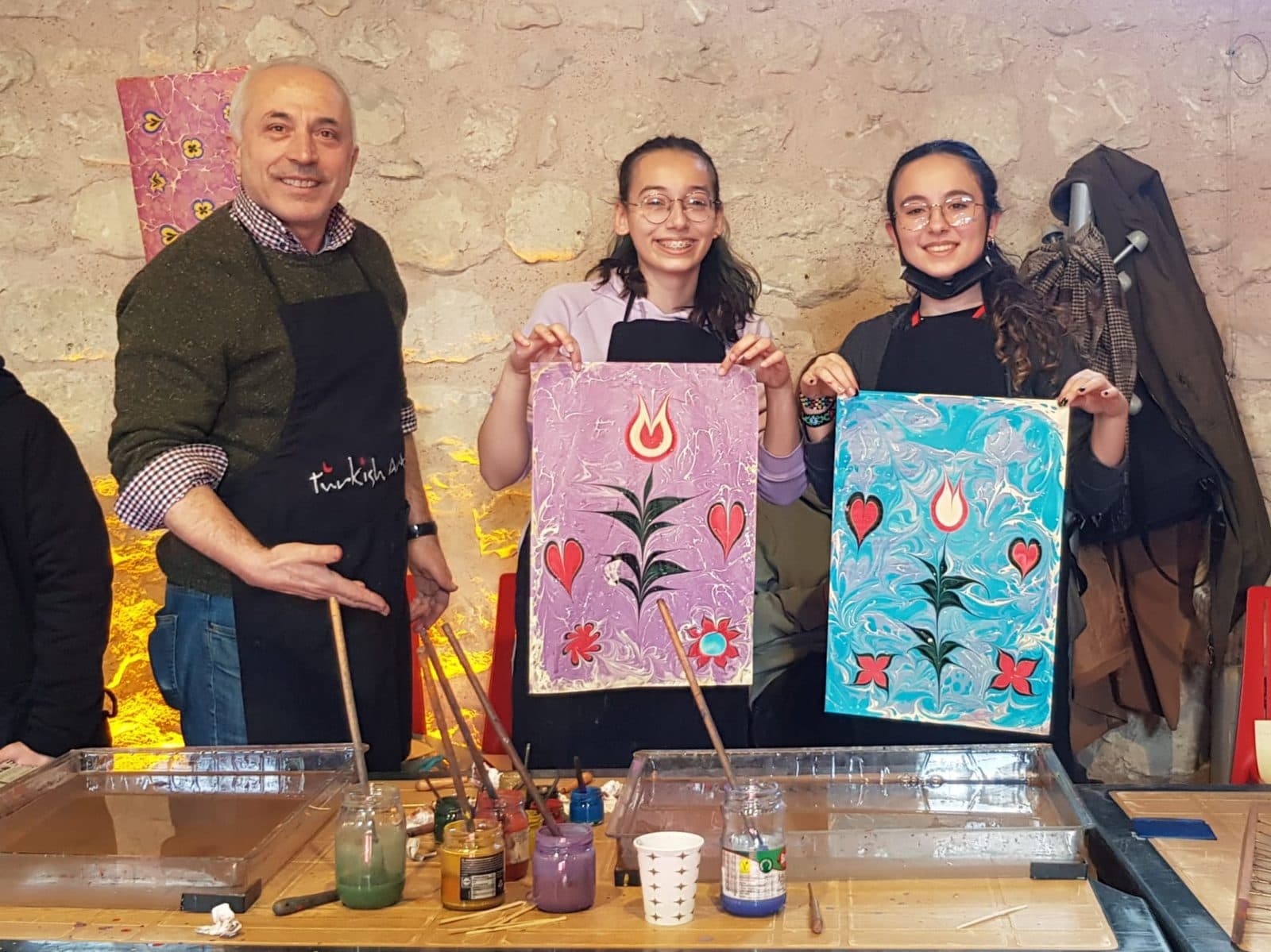 Teens holding tulip-and-heart marbling artworks